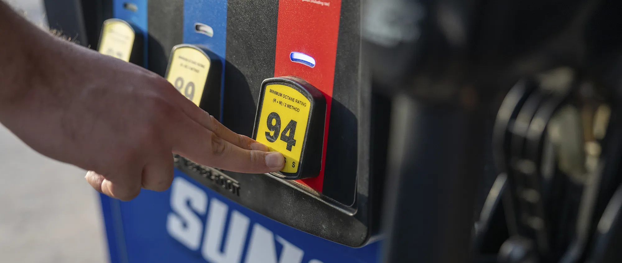 Person pressing 94 octane button at Sunoco pump