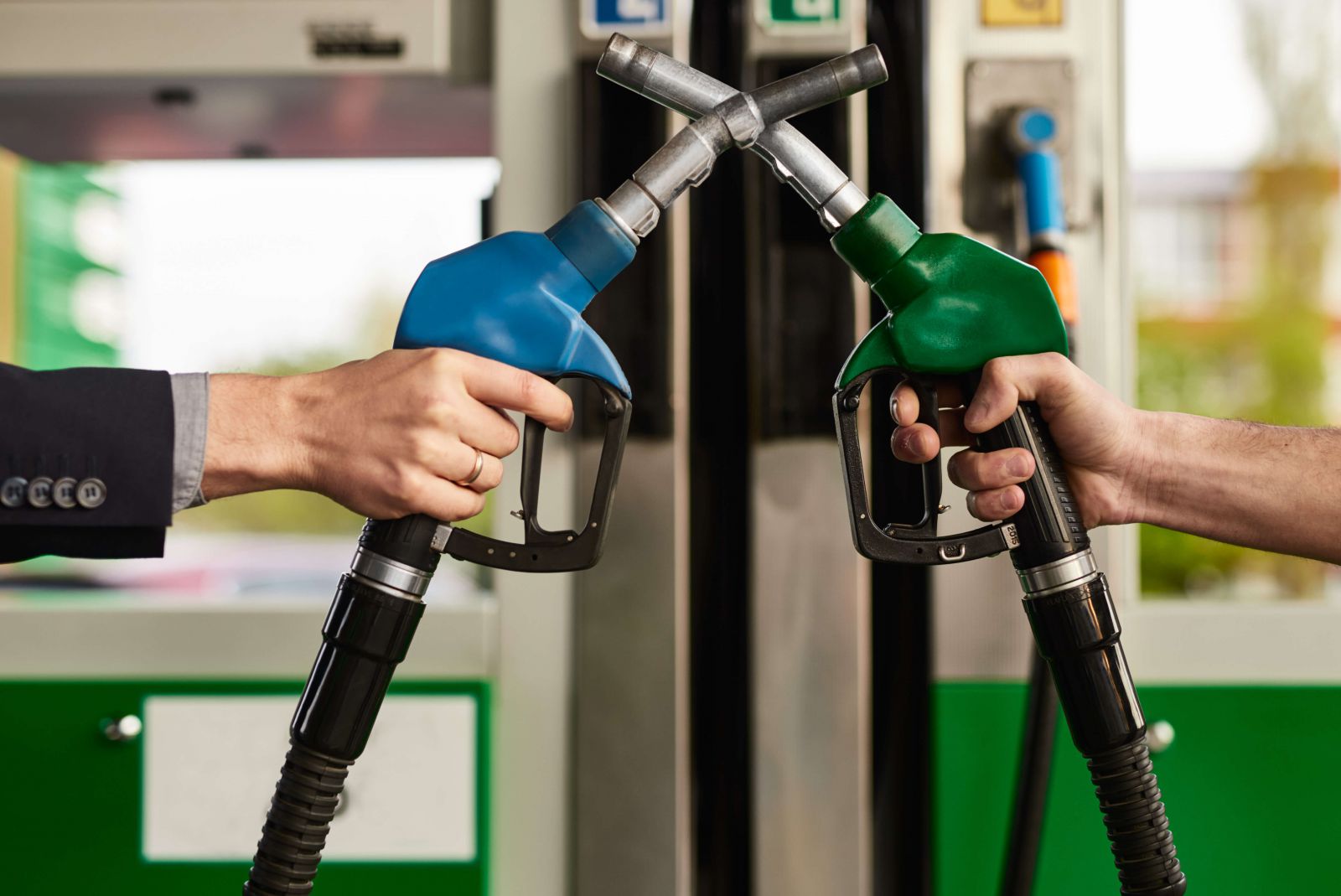 Men crossing gas pump nozzles