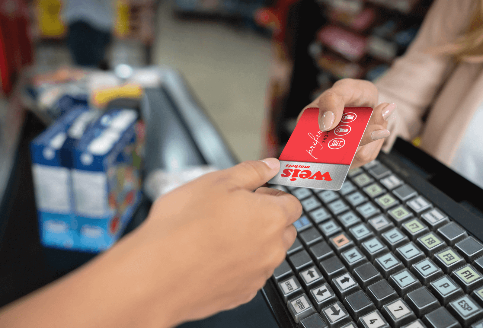 A customer hands over a red and gray Weis rewards card at a store checkout.