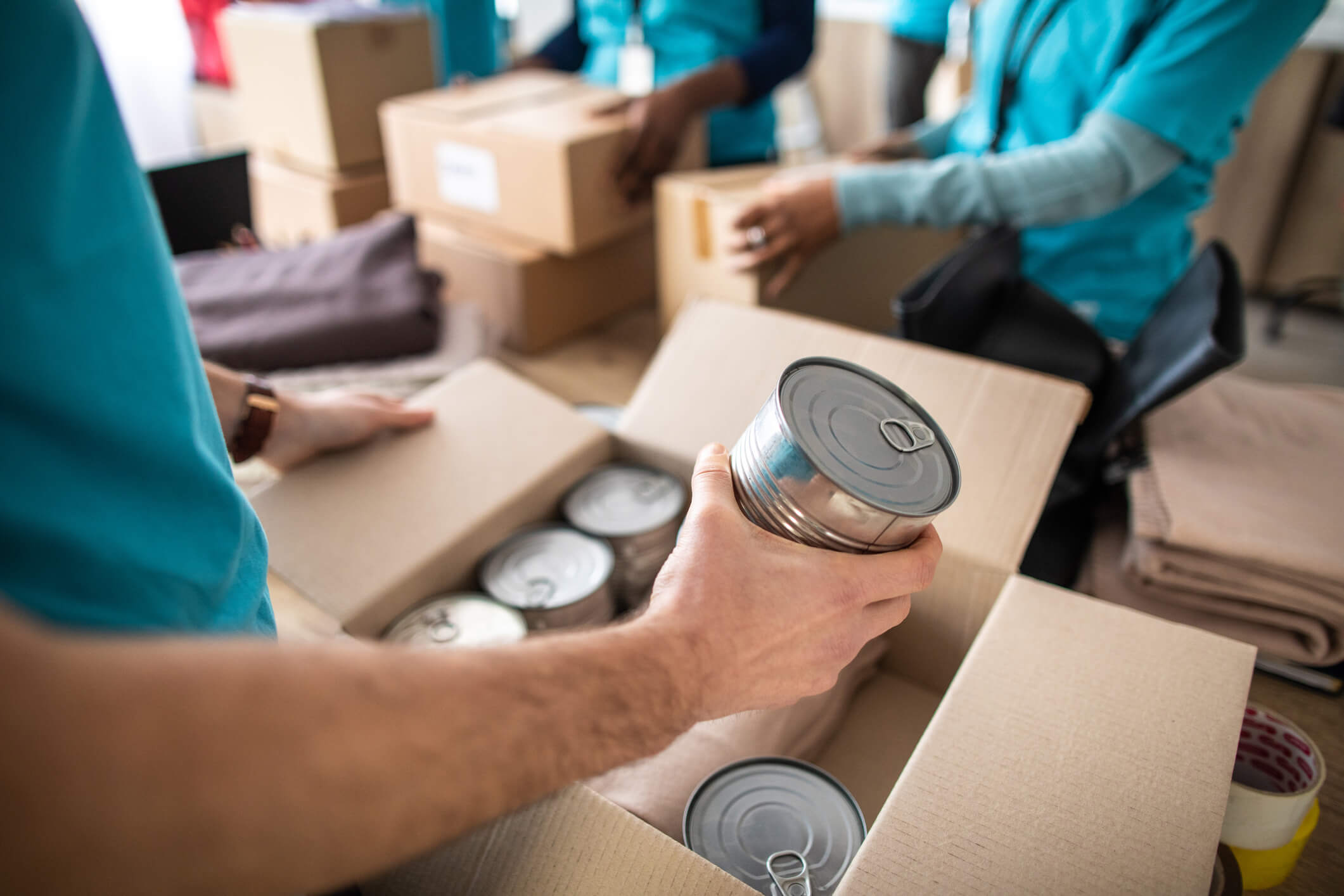 Volunteers packing canned goods into boxes at a food bank, supporting the fight against hunger.