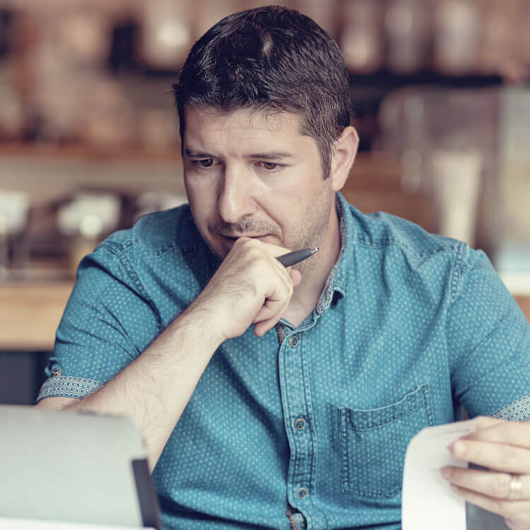 Man with pen looking at laptop